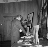 856628 Afbeelding van enkele mannen bij een stand met affiches en reclamemateriaal van de N.S. in de Commissarissenzaal ...